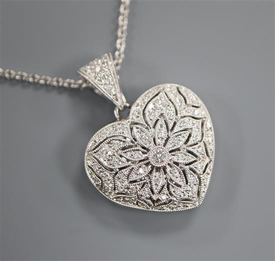 A modern pierced 18ct white gold and diamond encrusted heart shaped locket on an 18ct white gold fine link chain, gross 10.5 grams.